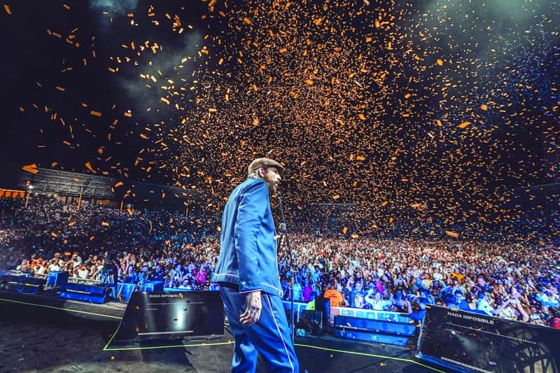 Juan Luis Guerra stands before the crowd as streamers fill the stadium